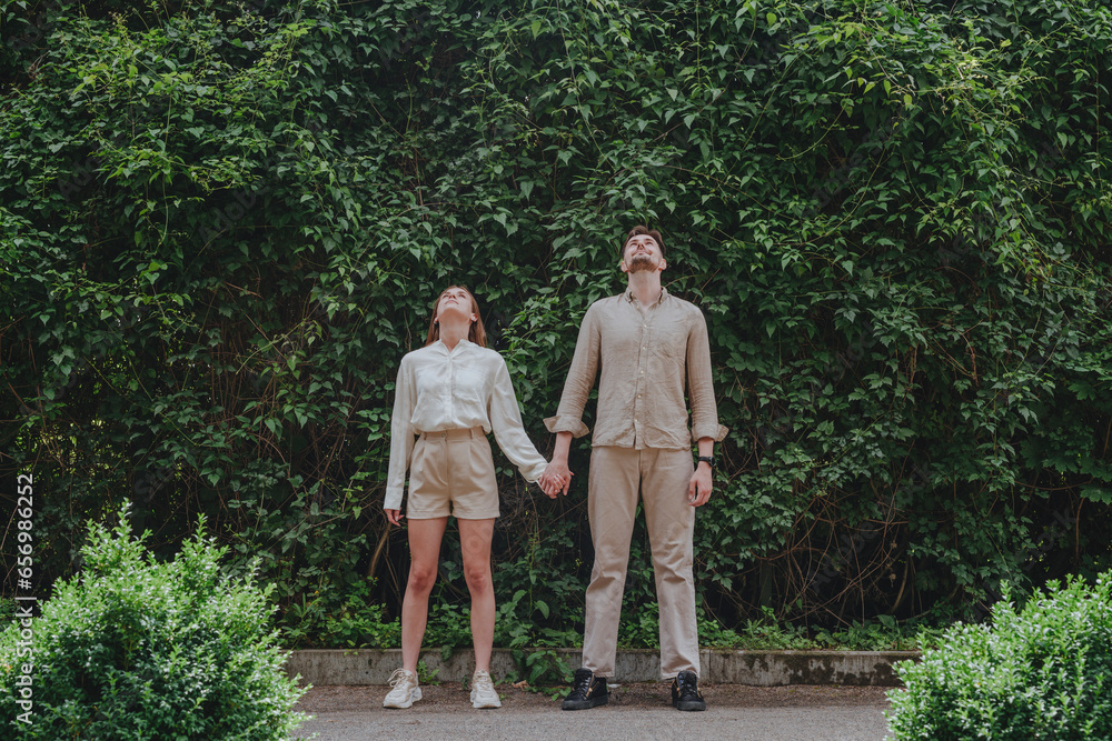 Young couple holding hands and looking up in garden Young couple holding hands and looking up in garden