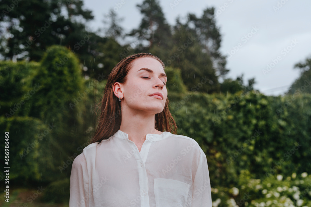 Young woman with eyes closed standing in rain at garden Young woman with eyes closed standing in rain at garden
