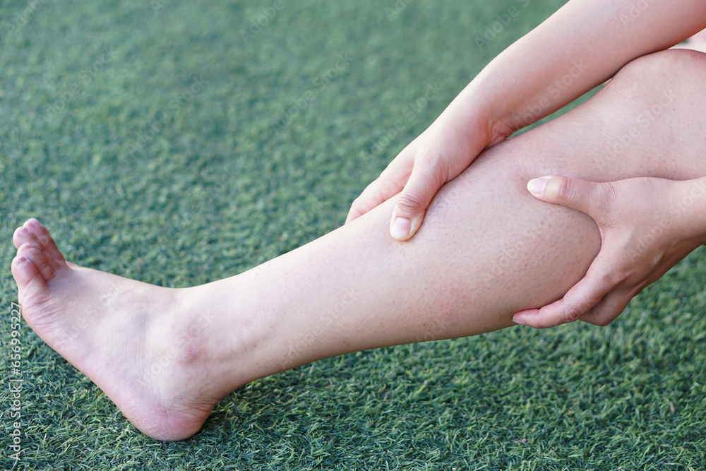 Closeup woman hands massage her calf because of cramping. Concept