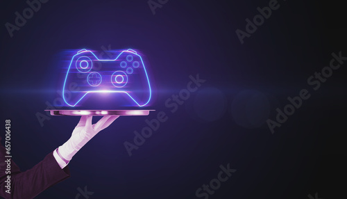 Closeup of businessman hand holding silver tray with creative joystick or gamepad hologram on blurry purple bokeh background. Esport, gaming and fun concept. photo
