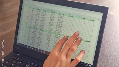 Slow motion footage of the woman hand scrolling touch screen of the laptop with loan amortization table open. Accounting