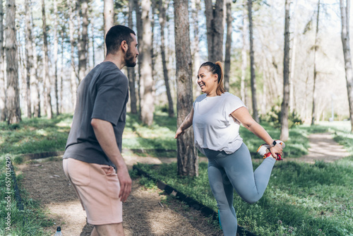 A beautiful, overweight female and her partner enjoy a revitalizing jog in the park, then take time to stretch and cool down, savoring the refreshing breeze