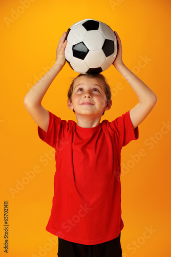 Teen boy soccer player with football ball against yellow background © fotofabrika
