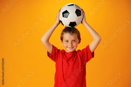 Teen boy soccer player with football ball against yellow background © fotofabrika