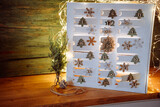 Christmas decoration with illuminated handmade advent calendar dedecorated with a string of lights on rustic wood. Eco friendly christmas packaging. Background for greeting cards with space for text.