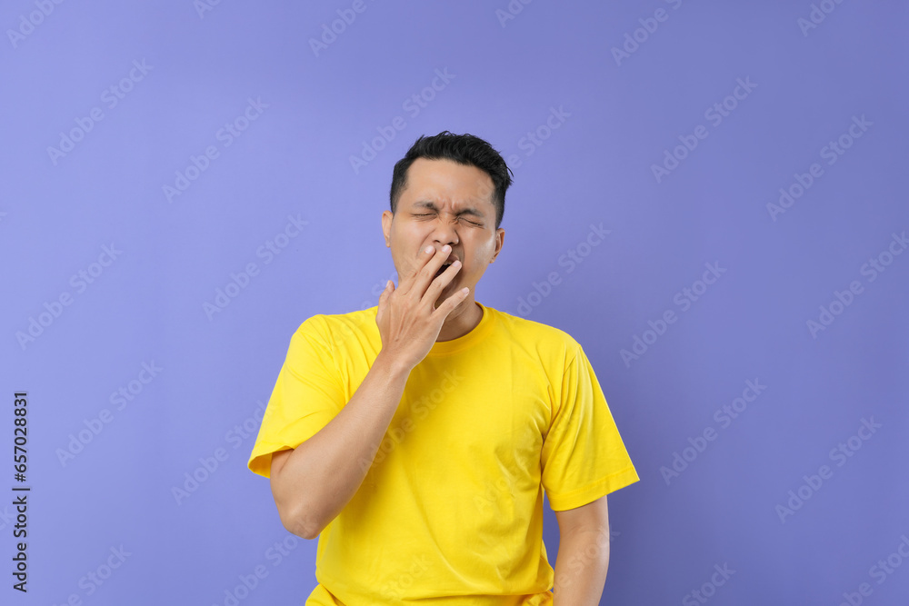 A tired Asian man feels sleepy covering his mouth and yawning. A tired Asian man feels sleepy covering his mouth and yawning.