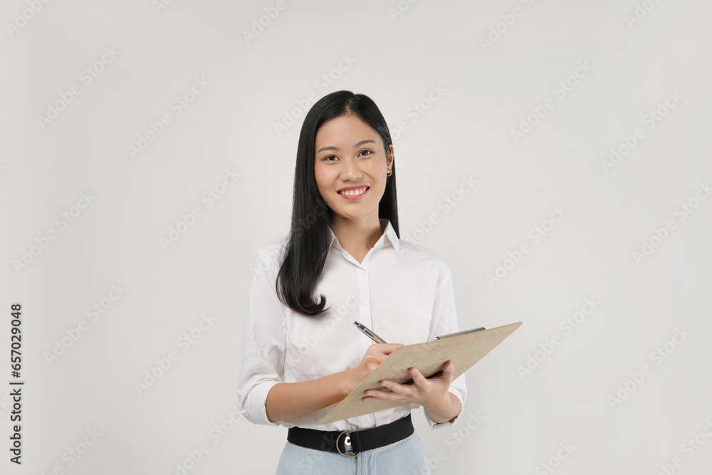 Photo of a young Asian woman in 20s holding a book and pen isolated on a white background. Photo of a young Asian woman in 20s holding a book and pen isolated on a white background.