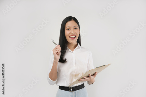 Photo of a young Asian woman in 20s holding a book and pen isolated on a white background.