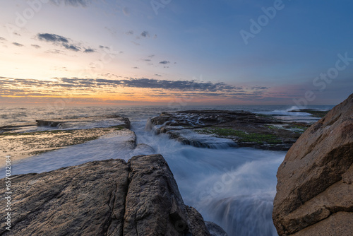 High tide water flowing into rock platform on the shore.