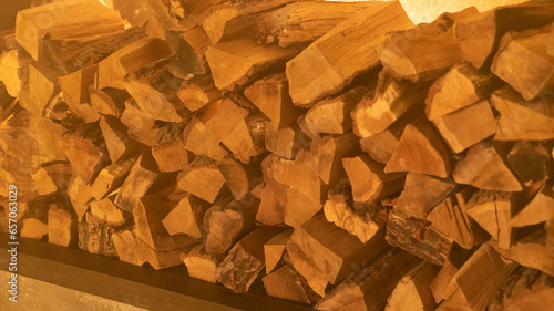 Firewood heap of natural timber in semi-dark room closeup. Dry woodpile stack prepared for domestic fireplace burning at home. Chopped lamber stock for fireside in house at warm light