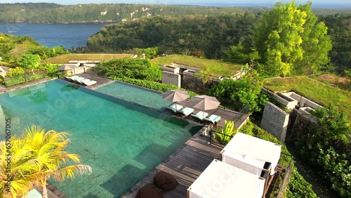 Aerial Tracking Woman Walking Along Swimming Pool in Tropical Hilltop Villa With Panoramic Overview of Gamat Bay at Maua Resort Nusa Penida in Bali, Indonesia photo
