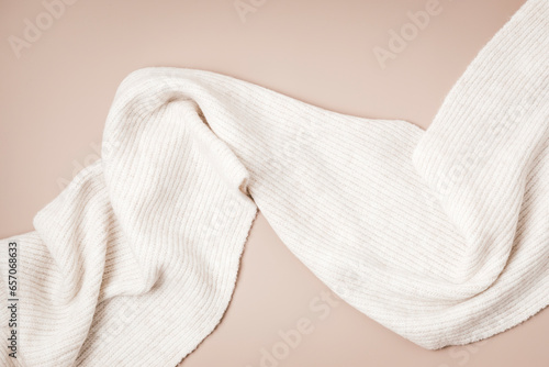 Beige woolen scarf on pastel background. Stylish woman outerwear. Winter fashion accessories