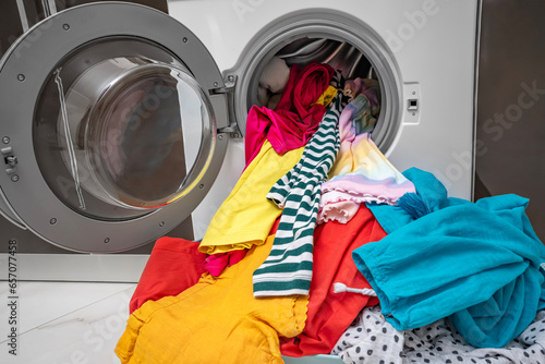 Multi-colored laundry for washing in the washing machine lies in the basket.