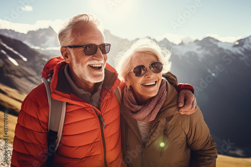 Two senior hikers wearing casual clothes admiring a scenic view from a mountain top. Adventurous old man and lady with backpacks. Hiking and trekking on a nature trail.
