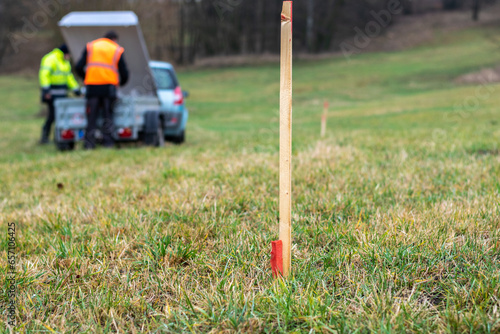 Fotografie Wood survey stake painted in red for work on construction site, workers in the b