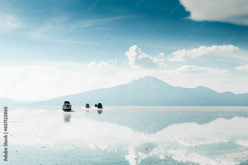 Off-road cars driving on Salar de Uyuni salt flat in Bolivia.
