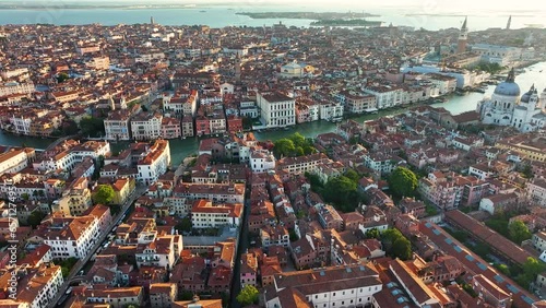 Forwards fly above Venice city skyline at sunrise, Grand Canal, golden hour, gondolas, boats, Venetian Lagoon, Italy