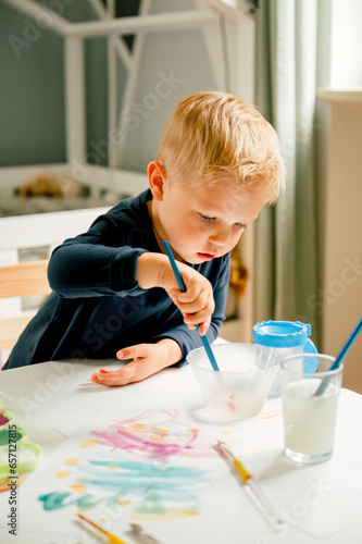 A male caucasian toddler is painting with watercolor