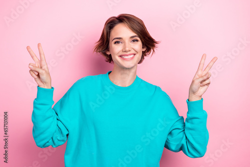 Photo of cute girl showing popular youth v sign gesture good mood wear oversize teal shirt isolated pink color background photo