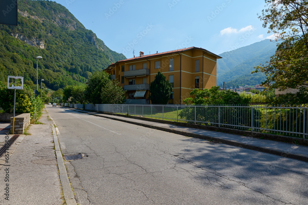 A road in Italian town in Lombardy with view of a residence or mansion against Italian Alps background