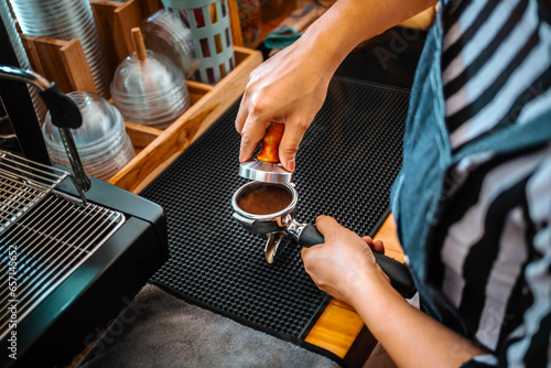 Top view of barista holding portafilter and coffee tamper making an espresso coffee in cafe photo