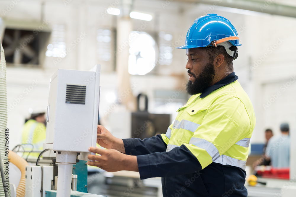 Male engineer worker control CNC machine at the industry factory. Male technician inspecting quality of machine in the factory