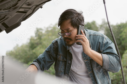 Man driver is using a mobile phone to call for help after car breakdown.