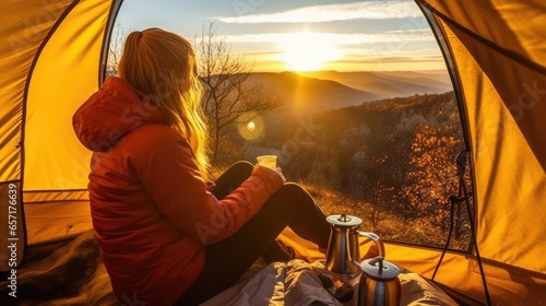 A happy smiling woman sits near a tent in an outdoor camping