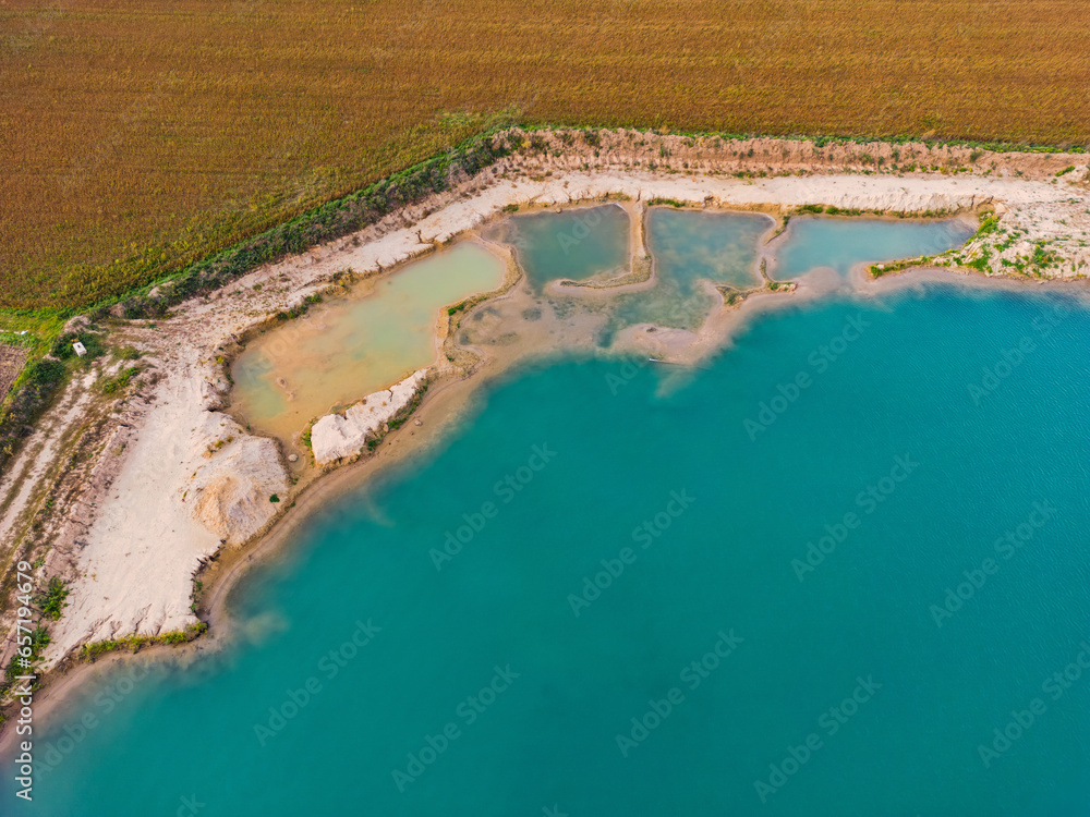Türkisfarbenes Wasser in einem Baggersee mit mehreren Becken am Ufer