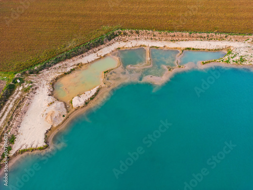 Türkisfarbenes Wasser in einem Baggersee mit mehreren Becken am Ufer