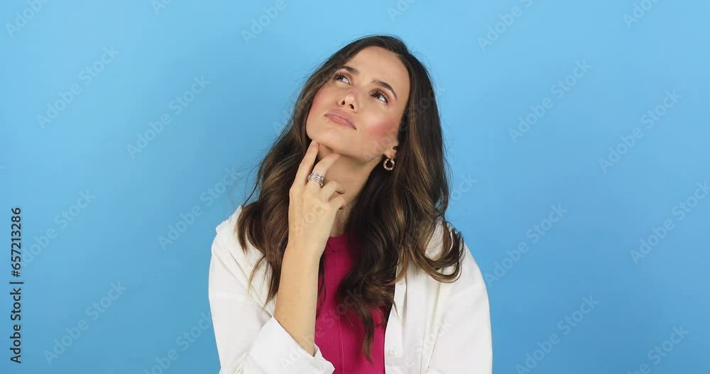 Pensive puzzled young girl thinking isolated on blue background. Looking aside up put hand prop up on chin, finger on lips. Thoughtful woman thinks deeply chooses or ponders plan, not sure, not know. Pensive puzzled young girl thinking isolated on blue background. Looking aside up put hand prop up on chin, finger on lips. Thoughtful woman thinks deeply chooses or ponders plan, not sure, not know.