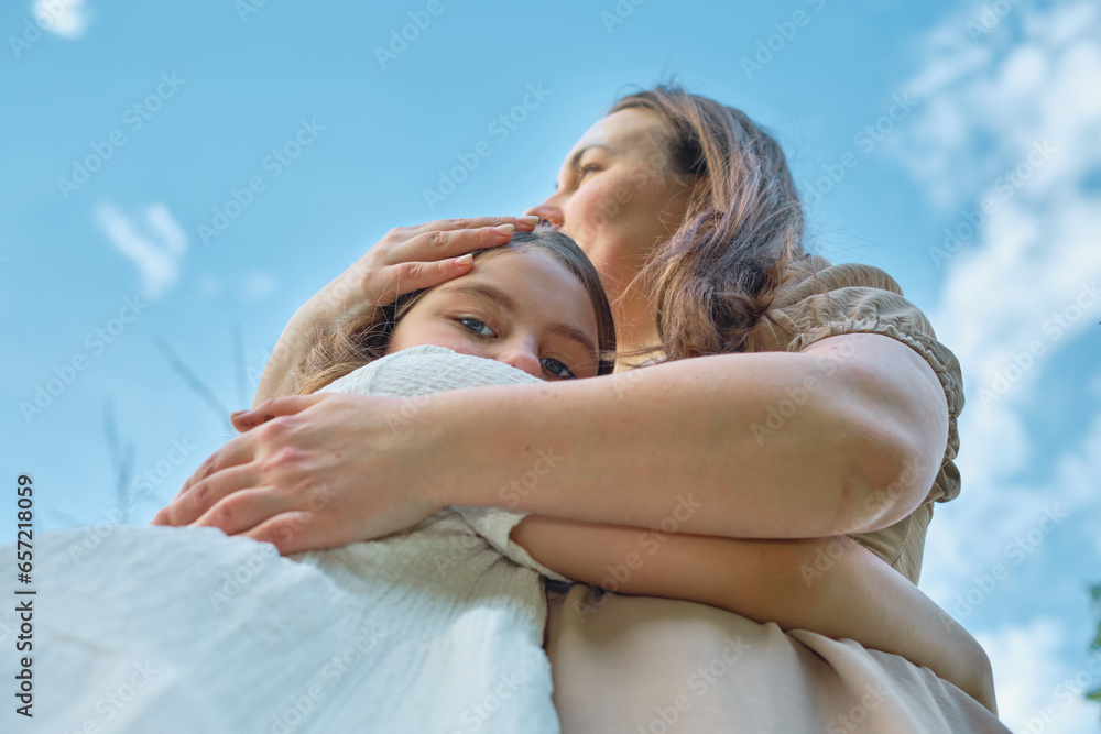 Against a backdrop of clear skies, a loving hug between mother and ...