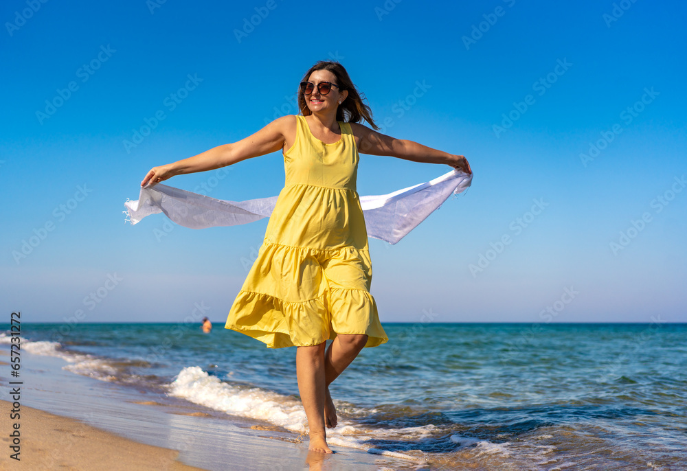 Happy beautiful woman holding shawl walking on sunny beach
Happy beautiful woman holding shawl walking on sunny beach