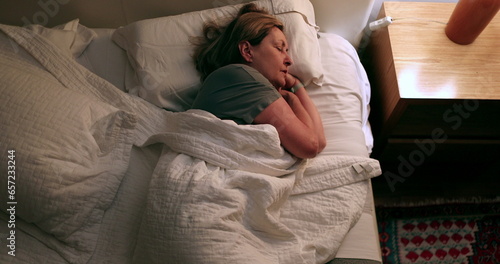 Quadro em tela Anxious woman unable to sleep turns on light on, tossing and turning in bed