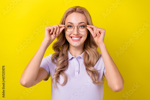 Portrait of cheerful clever nice girl toothy smile hands touch glasses isolated on yellow color background © deagreez