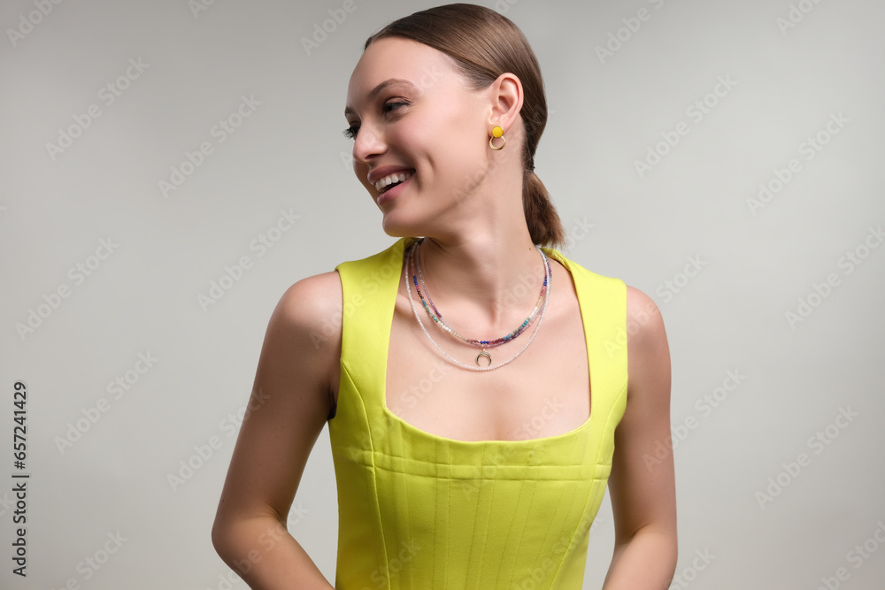 Close up portrait of a beautiful elegant woman with stylish jewelry on a white gray background. Girl in yellow dress Close up portrait of a beautiful elegant woman with stylish jewelry on a white gray background. Girl in yellow dress