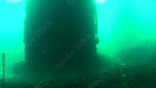 Sea pier, view from below. In the greenish water, the pillar of the Snake Island pier looks darkly. Black Sea, Ukraine. photo