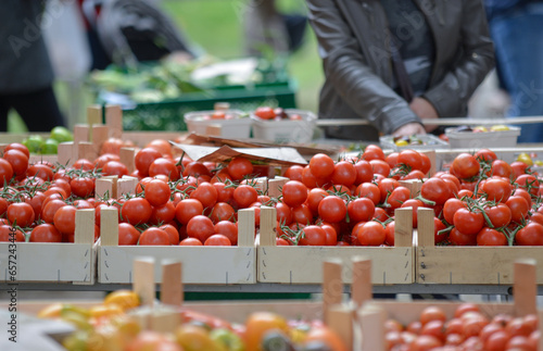Einkaufen auf dem Wochenmarkt: Blick auf Gemüsekisten mit unterschiedliche Sorten von Tomaten auf einem Markt draußen mit Menschen im verschwommenen Hintergrund, selektiver Fokus, Copyspace photo