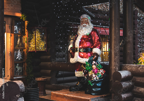 Santa Claus sitting on the porch of a wooden house with Christmas decorations