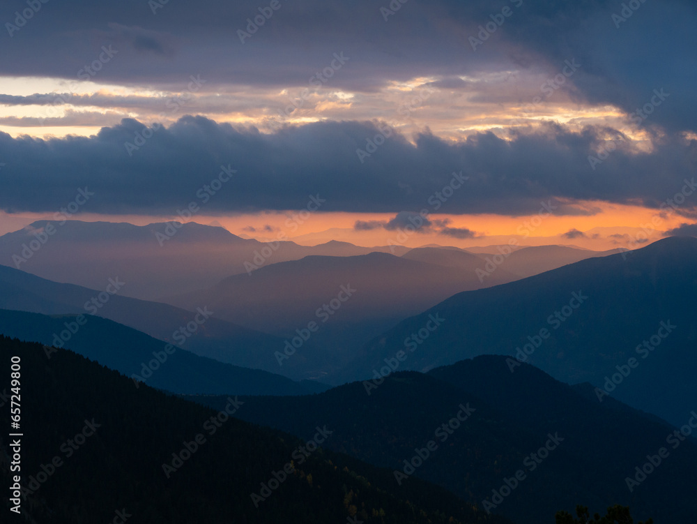 Atmospheric view with layers of mountains and clouds bathed in the colors of the sunset