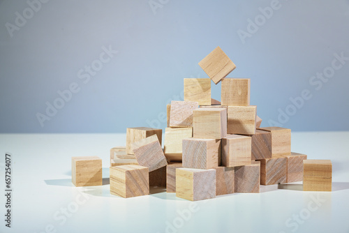 Teamwork with a broad base is the way up  heap of wooden cubes holding one of them on the top  concept for togetherness in business and organizations  gray background
