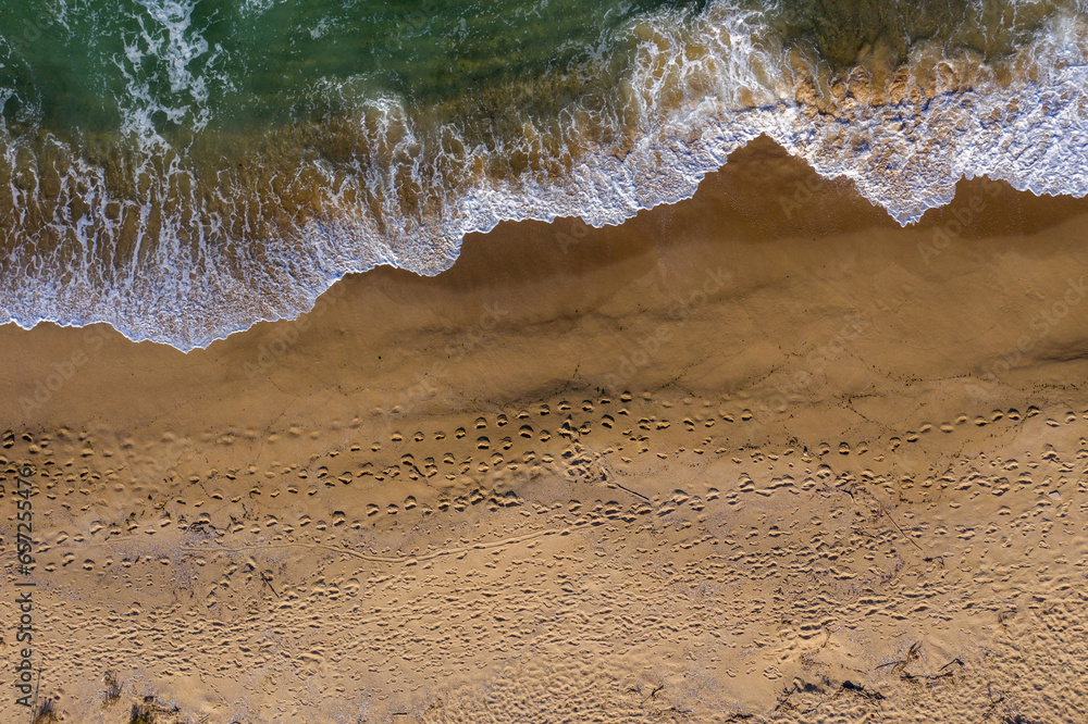 Aerial view of a remote sandy beach and sea waves
