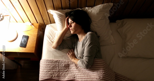 Tableau sur toile Woman suffering from insomnia turns light ON and picks up cellphone