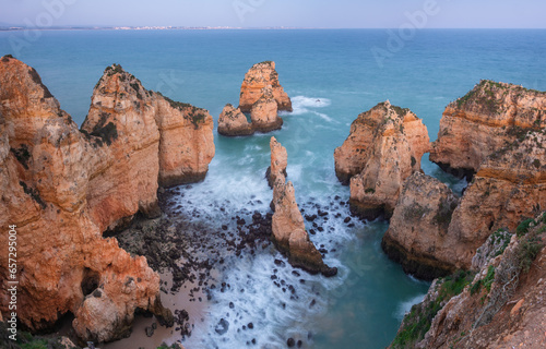 Long exposure image of the rocky Algarve coast with steep cliffs in the vicinity of the village of Lagos, Portugal in the blue hour after sunset  © Chris