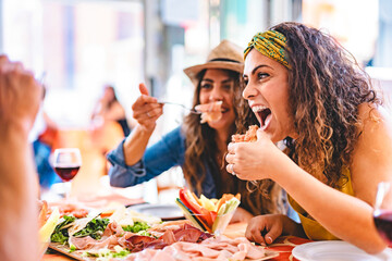 Young people dining at restaurant and having fun drinking red wine together sitting outside at pub terrace-Cheerful People with food laughing and enjoying at happy hour 