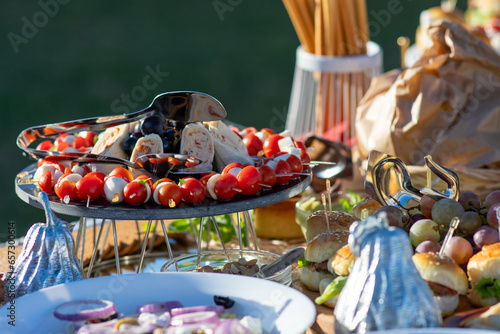A table full of various dishes, small bites, outdoor party catering spread.