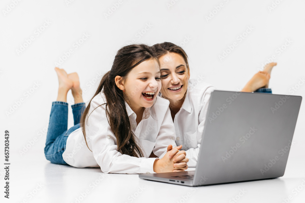 Happy family mother and cute little daughter laughing while having fun with laptop and video chatting with relatives or friends. The family experiences joy while spending time together. Happy family mother and cute little daughter laughing while having fun with laptop and video chatting with relatives or friends. The family experiences joy while spending time together.