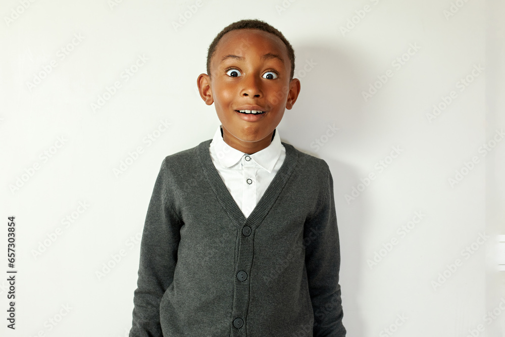 Amazed, shocked, astonished black school kid in cardigan standing against white studio background with big round eyes and surprised overjoyed facial expression after winning abroad study grant Amazed, shocked, astonished black school kid in cardigan standing against white studio background with big round eyes and surprised overjoyed facial expression after winning abroad study grant