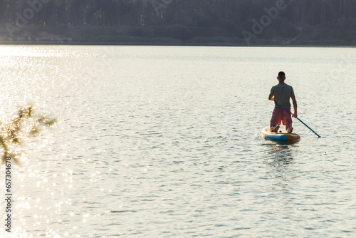 Man silhouette on the supboard on the middle of the lake. photo