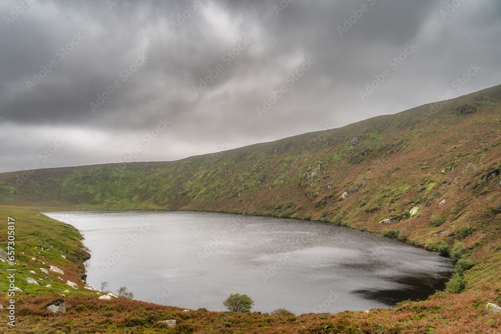 Lake, Lough Bray surrounded by mountains and covered in moody, dramatic storm clouds. Hiking in Wicklow Mountains, Ireland